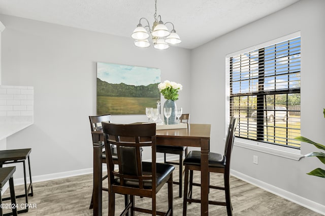 dining space with hardwood / wood-style floors, a textured ceiling, and a chandelier