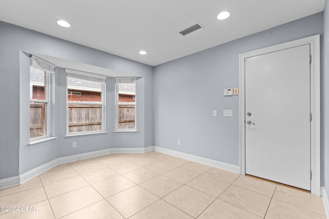 unfurnished room with light tile patterned floors and a textured ceiling