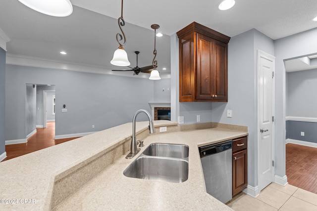 kitchen with dishwasher, sink, light hardwood / wood-style floors, decorative light fixtures, and a fireplace