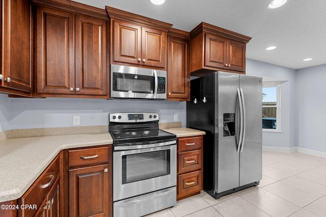 kitchen with appliances with stainless steel finishes, a textured ceiling, and light tile patterned floors