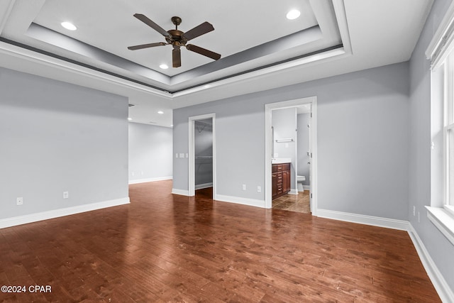 unfurnished room featuring dark hardwood / wood-style floors, ceiling fan, and a tray ceiling