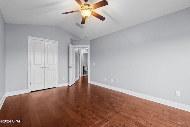 unfurnished bedroom featuring ceiling fan, a closet, dark wood-type flooring, and vaulted ceiling