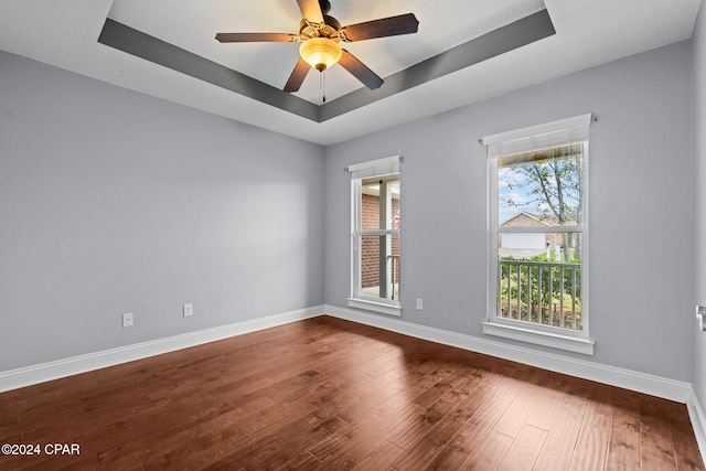 unfurnished room featuring a tray ceiling, ceiling fan, wood-type flooring, and a textured ceiling