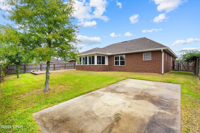 rear view of property featuring a lawn and a patio area