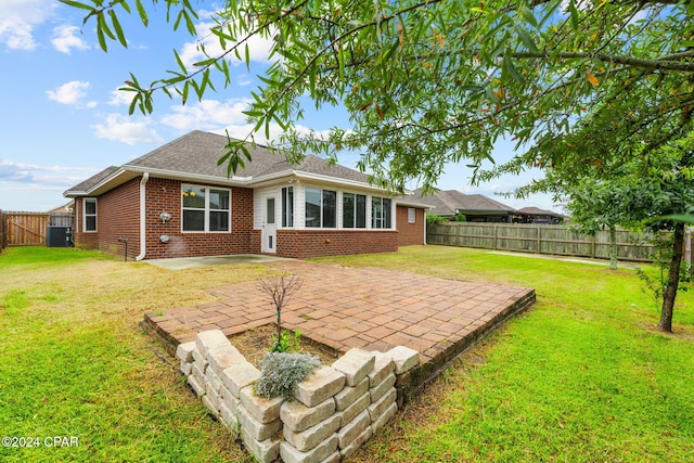 back of property with central AC unit, a patio area, and a lawn