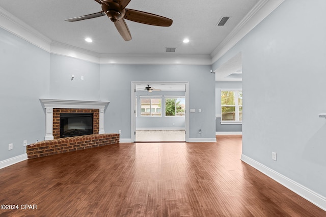 unfurnished living room featuring ceiling fan, wood-type flooring, crown molding, and a brick fireplace