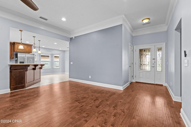 foyer featuring a textured ceiling, light hardwood / wood-style floors, and crown molding