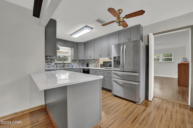 kitchen featuring gray cabinetry, stainless steel appliances, kitchen peninsula, and backsplash