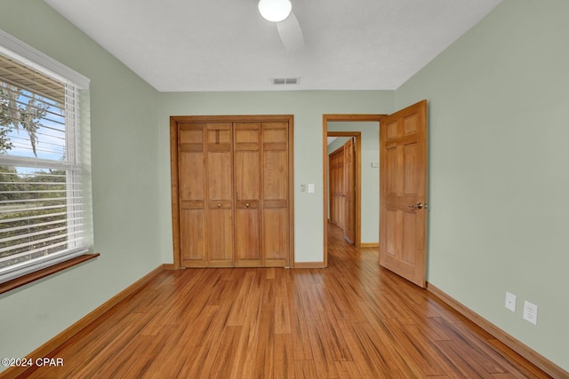 unfurnished bedroom featuring ceiling fan, a closet, and light wood-type flooring