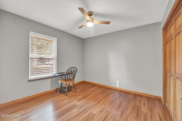 living area with a textured ceiling, light hardwood / wood-style floors, and ceiling fan