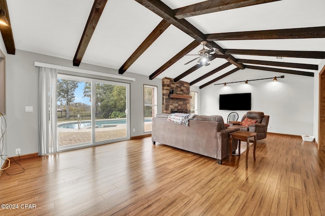 living room featuring lofted ceiling with beams, ceiling fan, a fireplace, and light hardwood / wood-style flooring