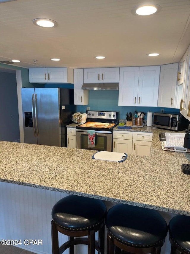 kitchen featuring a breakfast bar area, white cabinetry, and appliances with stainless steel finishes