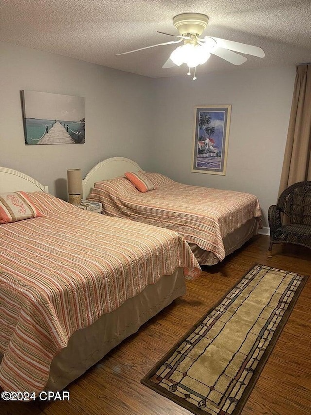 bedroom featuring ceiling fan, dark hardwood / wood-style floors, and a textured ceiling