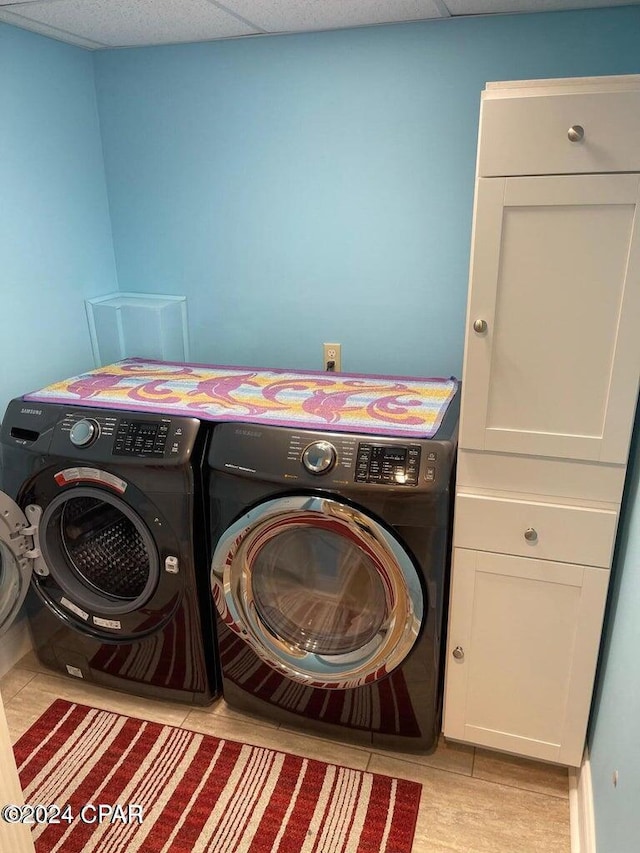 clothes washing area with cabinets and washing machine and clothes dryer