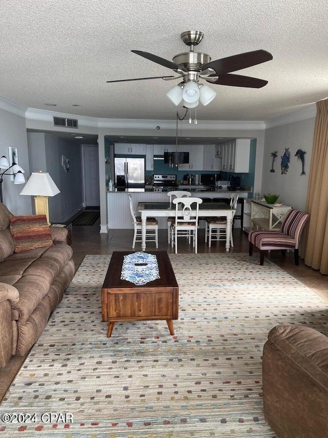 living room featuring ceiling fan, ornamental molding, and a textured ceiling