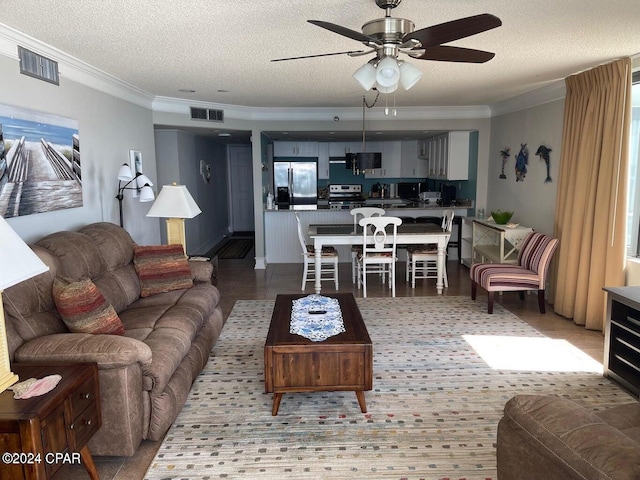 living room featuring ceiling fan, a textured ceiling, and ornamental molding