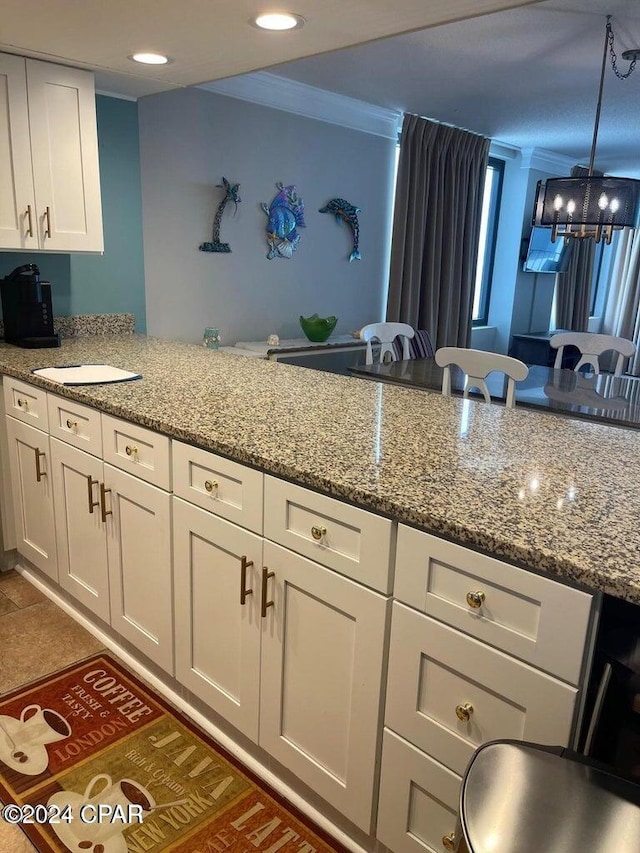 kitchen featuring white cabinets, decorative light fixtures, light stone countertops, and kitchen peninsula