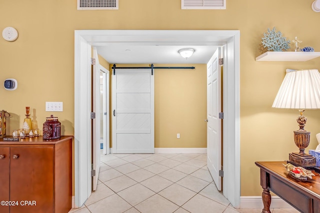 corridor featuring a barn door and light tile patterned flooring