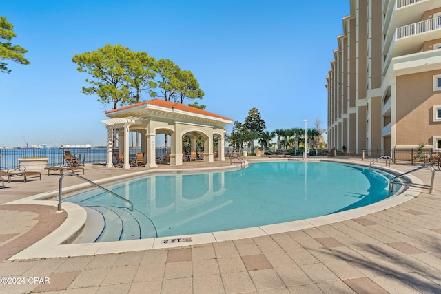 view of pool featuring a water view and a patio area