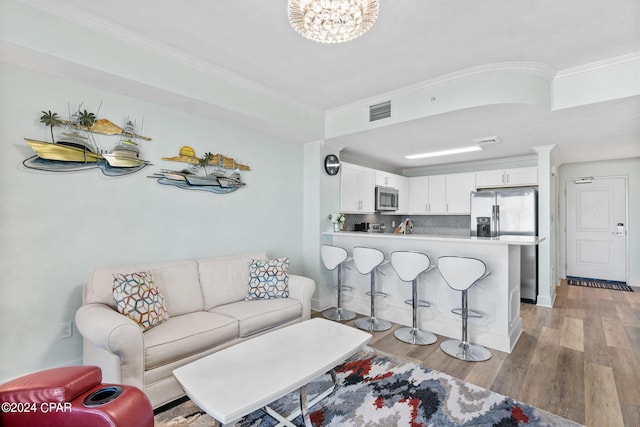 living room featuring light hardwood / wood-style floors, an inviting chandelier, and crown molding