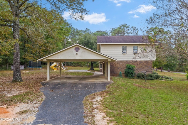 view of front facade with a front lawn, a trampoline, and a carport