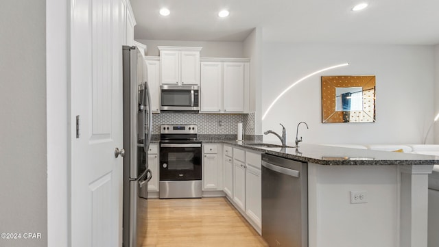 kitchen with white cabinetry, kitchen peninsula, appliances with stainless steel finishes, and sink