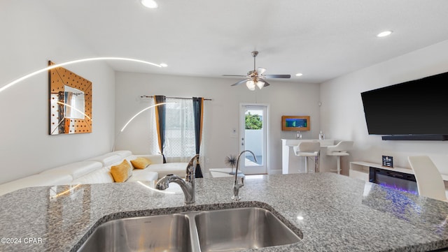 kitchen featuring stone counters, sink, and ceiling fan