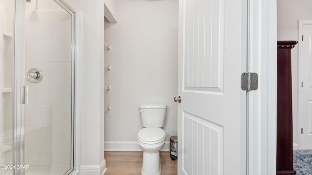 bathroom featuring toilet, hardwood / wood-style flooring, and a shower with shower door