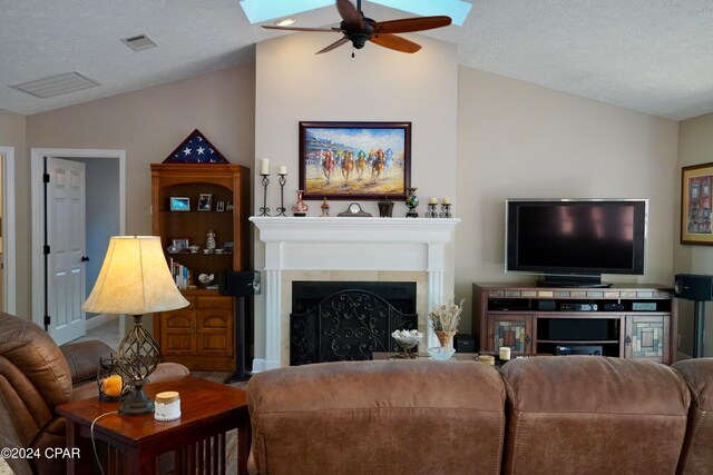 living room featuring vaulted ceiling, ceiling fan, and a textured ceiling