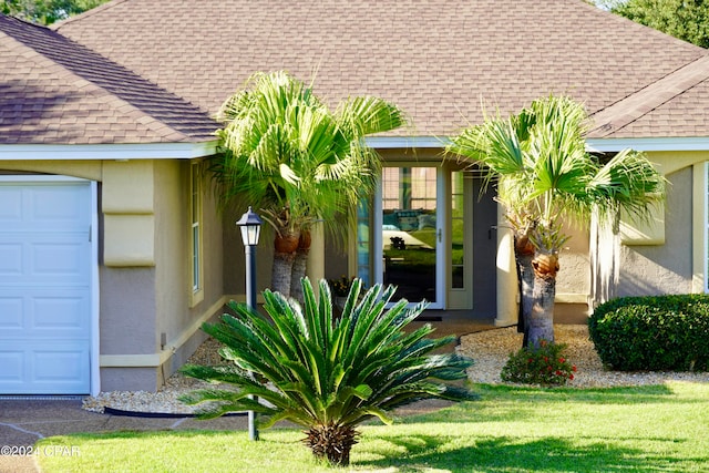 entrance to property with a garage and a lawn