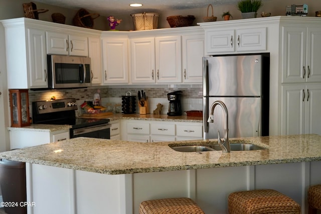 kitchen with white cabinets, appliances with stainless steel finishes, a breakfast bar area, and sink