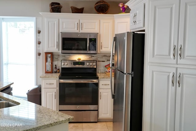 kitchen featuring white cabinetry, stainless steel appliances, tasteful backsplash, and light stone countertops