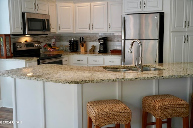 kitchen featuring white cabinets, a kitchen bar, and stainless steel appliances