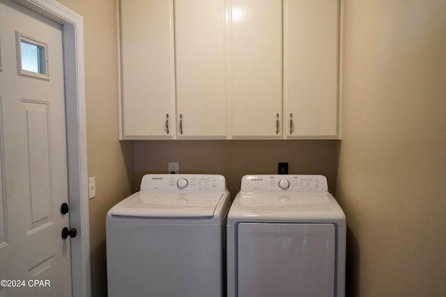 clothes washing area featuring cabinets and washer and dryer