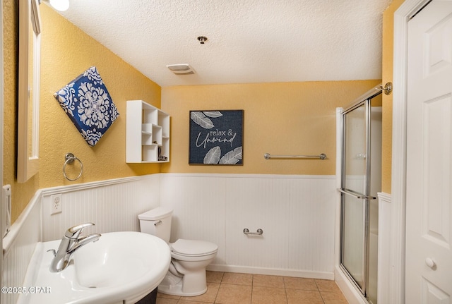 bathroom with sink, tile patterned flooring, walk in shower, toilet, and a textured ceiling