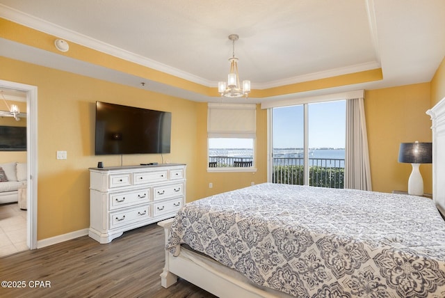 bedroom with ornamental molding, dark hardwood / wood-style floors, a notable chandelier, and a tray ceiling