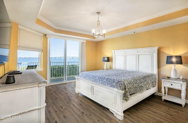 bedroom featuring a water view, dark hardwood / wood-style flooring, a raised ceiling, and access to outside