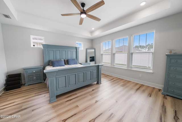 bedroom featuring a tray ceiling, ceiling fan, and light hardwood / wood-style flooring