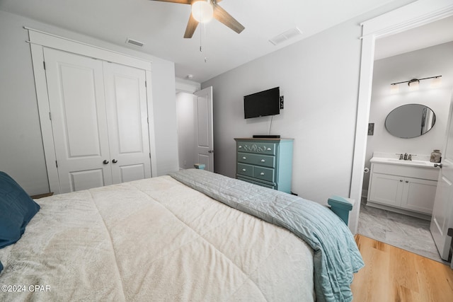 bedroom with a closet, connected bathroom, sink, ceiling fan, and light hardwood / wood-style flooring