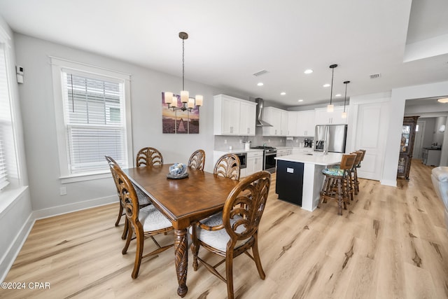 dining space with light hardwood / wood-style flooring and an inviting chandelier