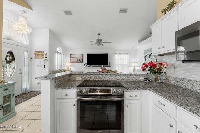 kitchen with white cabinets, stainless steel electric range, decorative backsplash, light tile patterned floors, and ceiling fan with notable chandelier