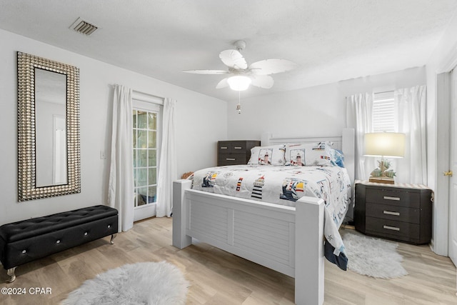 bedroom featuring a textured ceiling, light hardwood / wood-style flooring, multiple windows, and ceiling fan