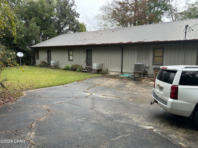 ranch-style house with central air condition unit and a front lawn