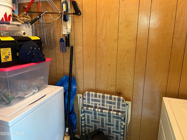 laundry room featuring washing machine and clothes dryer and wood walls