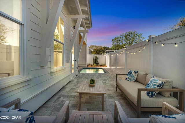 patio terrace at dusk featuring a fenced in pool and an outdoor hangout area