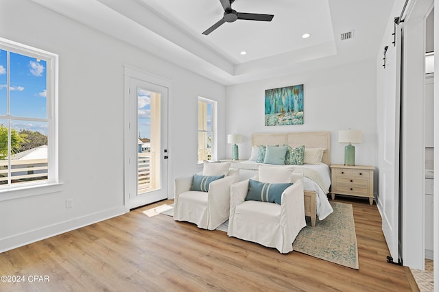 bedroom with a barn door, light wood-type flooring, access to outside, and ceiling fan