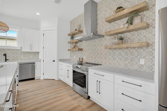 kitchen with tasteful backsplash, white cabinets, stainless steel appliances, and wall chimney exhaust hood