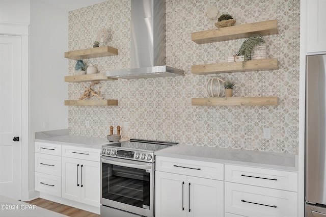 kitchen with wall chimney exhaust hood, white cabinetry, tasteful backsplash, light wood-type flooring, and stainless steel appliances