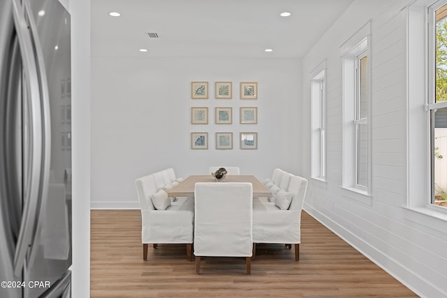 dining area with a wealth of natural light, wood-type flooring, and brick wall