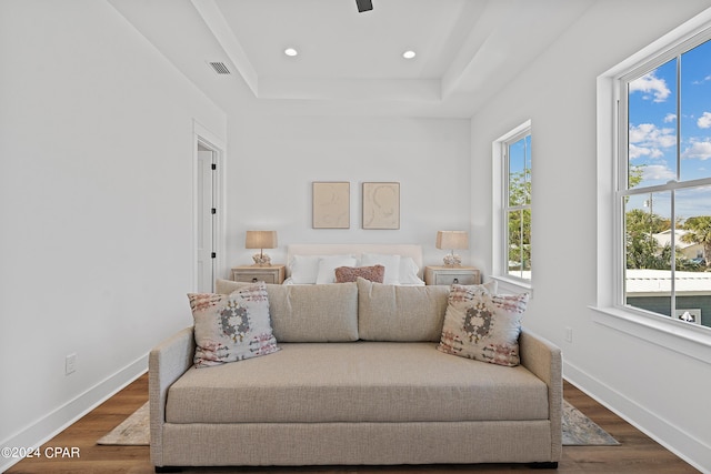 bedroom featuring ceiling fan, dark hardwood / wood-style flooring, a raised ceiling, and multiple windows